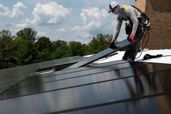 An employee with Ipsun Solar installs solar panels on the roof of the Peace Lutheran Church in Alexandria, Virginia on May 17, 2021. - Using donations, the church installed a 60.48 kilowatt solar instillation to bring down their carbon footprint. US President Joe Biden has called for the US energy sector to be fully decarbonized by 2035. To this end, he has asked Congress for $100 billion to invest in the national grid and shift to cleaner energy, as well as a ten-year extension of tax credits for renewable generation and storage. "The tax credit for wind and solar has been quite successful in creating a large scale investment and build out," Dan Lashof, president of the World Resources Institute told AFP, welcoming the extension. (Photo by Andrew CABALLERO-REYNOLDS / AFP) (Photo by ANDREW CABALLERO-REYNOLDS/AFP via Getty Images)